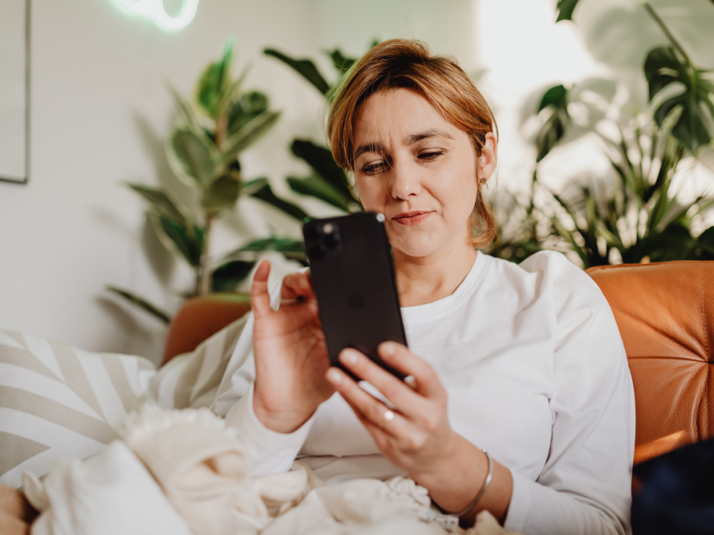 Kobieta patrząca w telefon czuje zazdrość w biznesie - mechanizm Złotego Cienia.